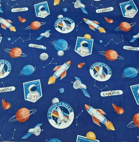 Tissu bleu avec motifs de fusées, planètes et astronautes sur un fond étoilé.