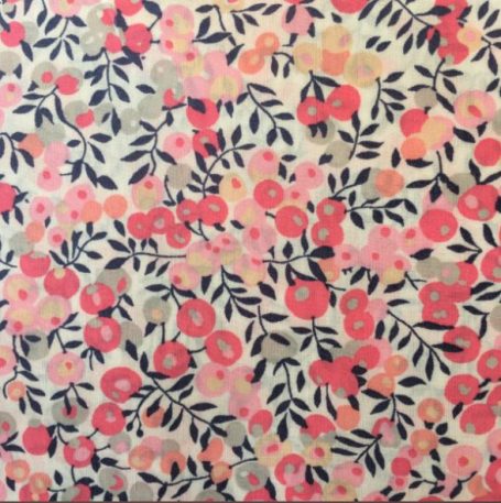 Tissu à fleurs roses et rouges sur fond clair avec des feuillages verts. liberty